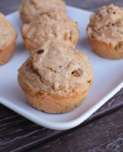 Close-up of a spelt muffin showing bits of nuts inside with more muffins on the platter.