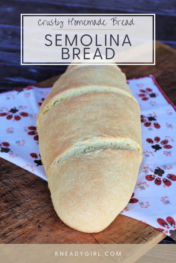 An oblong loaf of bread sit on top of a printed cloth. Text overlay reads: Crusty Homemade Bread - Semolina Bread.