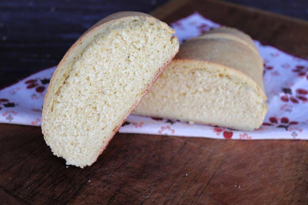 A loaf of semolina bread that has been sliced in half. The halves stacked on each other exposing the insides. 