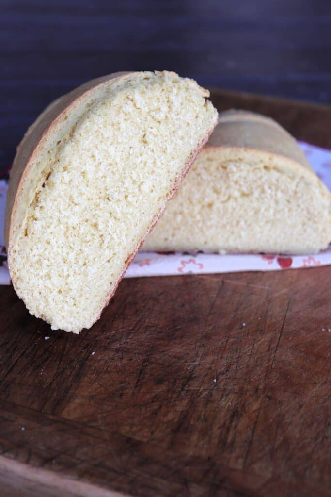 A loaf of semolina bread that has been sliced in half. The halves stacked on each other exposing the insides. 