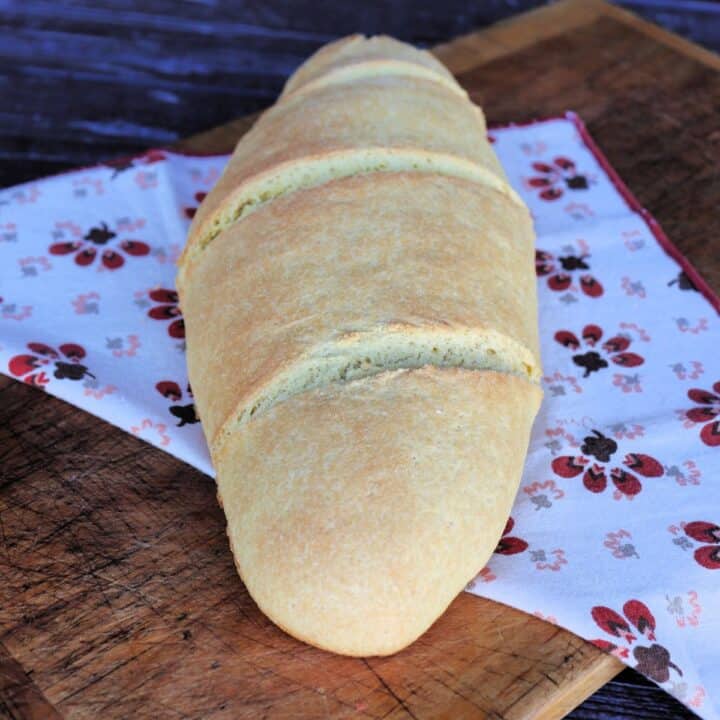 An oblong loaf of semolina bread sits on a printed cloth.
