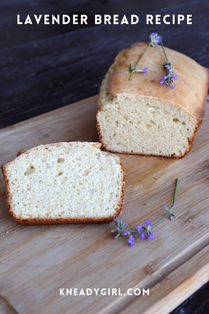 Slices of bread on a board with remaining loaf behind them. Fresh lavender flowers sit on the board and loaf. Text overlay reads: Lavender Bread Recipe.