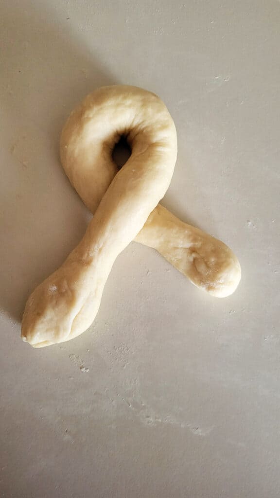 A raw piece of bread dough in a u-shape with the ends crossed.