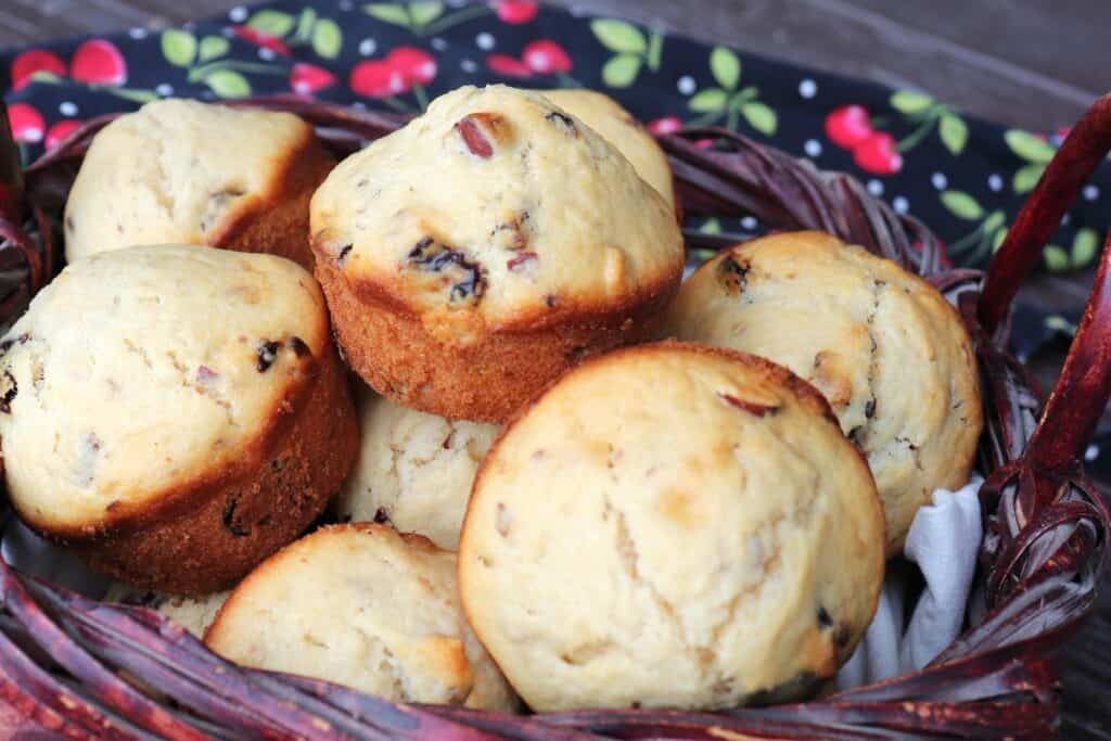 Close-up of a dried cherry muffin sitting on top of more muffins stacked in a basket.