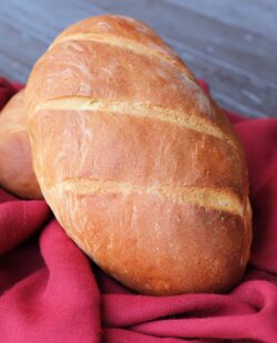 A loaf of Italian bread sits on a red cloth.