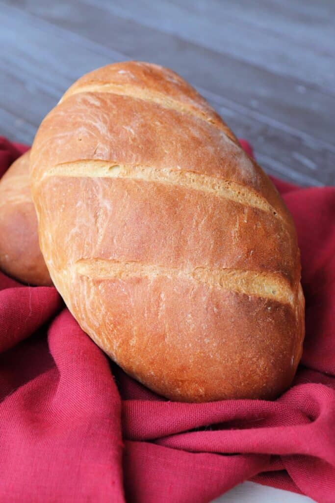 A loaf of Italian bread sits wrapped in a red cloth.