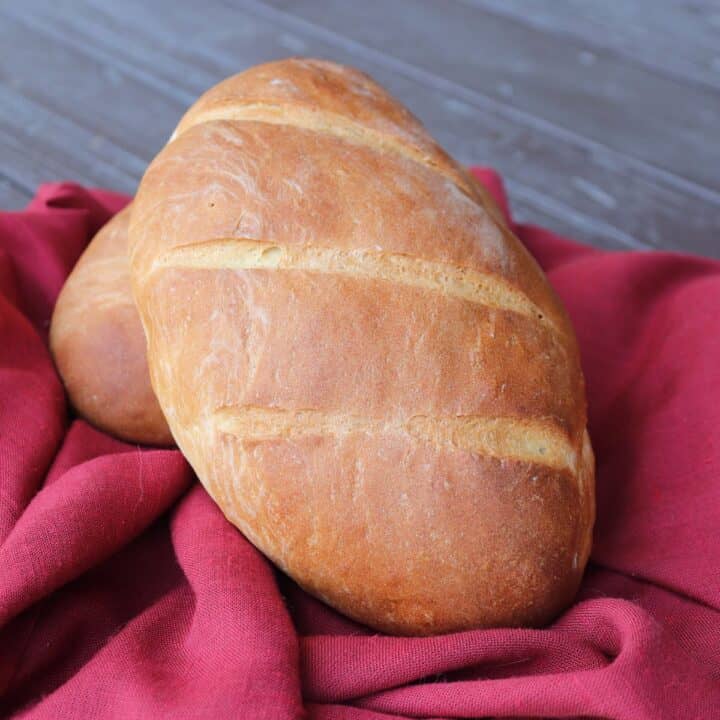 A loaf of bread sitting on a read cloth.