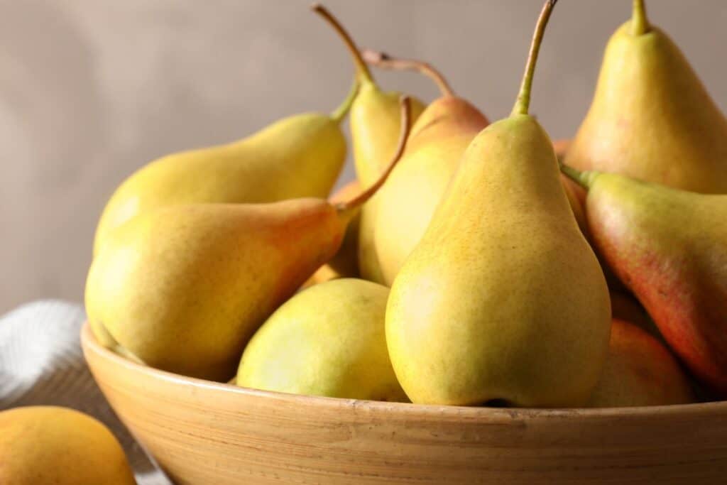 Fresh pears in a bowl sitting on a table.