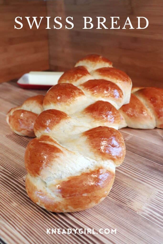 A loaf of braided sits at an angle on top of another loaf. A butter dish in the background. Text overlay reads: Swiss Bread.