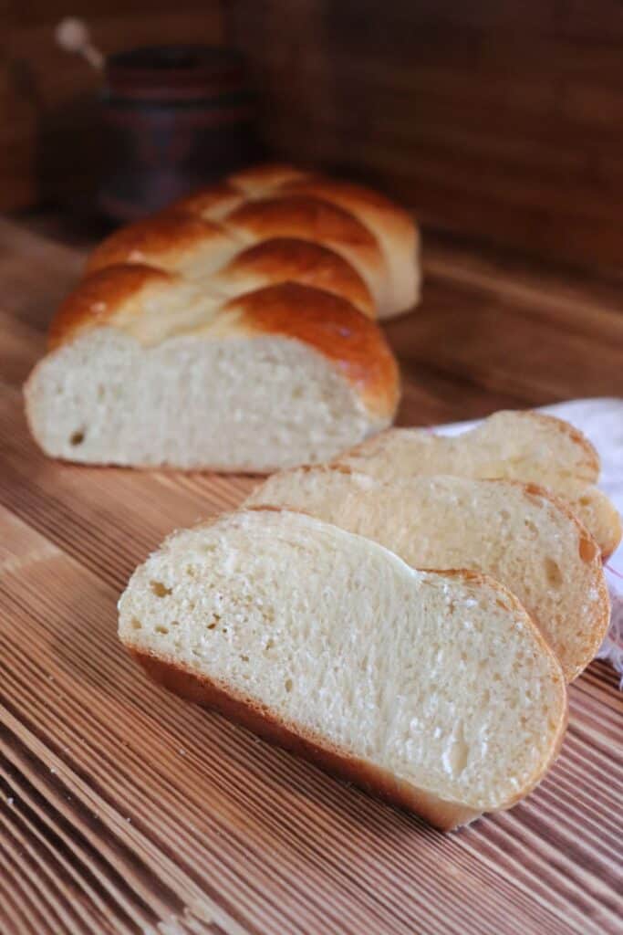 Slices of Swiss bread sit on a board, the remaining loaf sits behind them. 