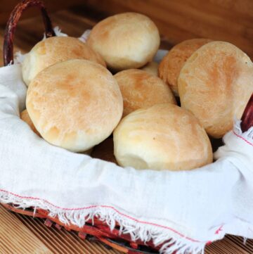 Dinner rolls stacked inside a basket on a table.