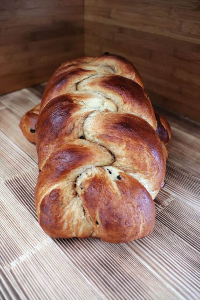 A loaf of braided bread sits on an angle propped up on another loaf of bread. 