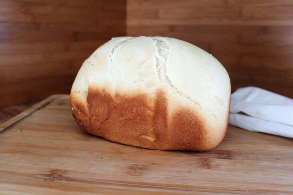 A loaf of hawaiian bread is seen from the side and sits on a board.