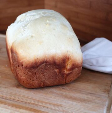 A loaf of sweet Hawaiian bread sits on a board and is seen from the side.