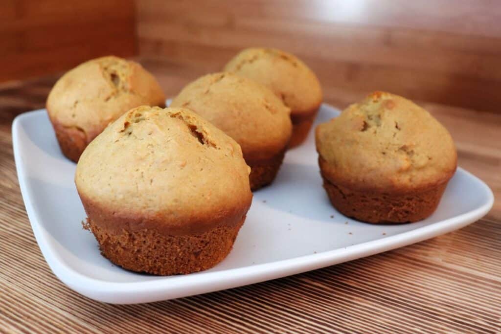 A plate full of sweet potato muffins sits on a table.