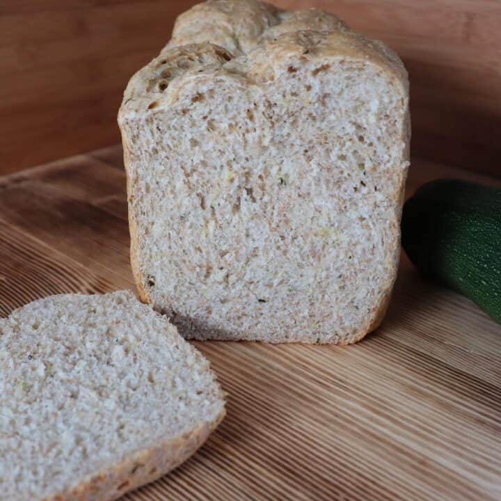 A loaf of bread that has the end cut off sits on a board with the heel in front of it.