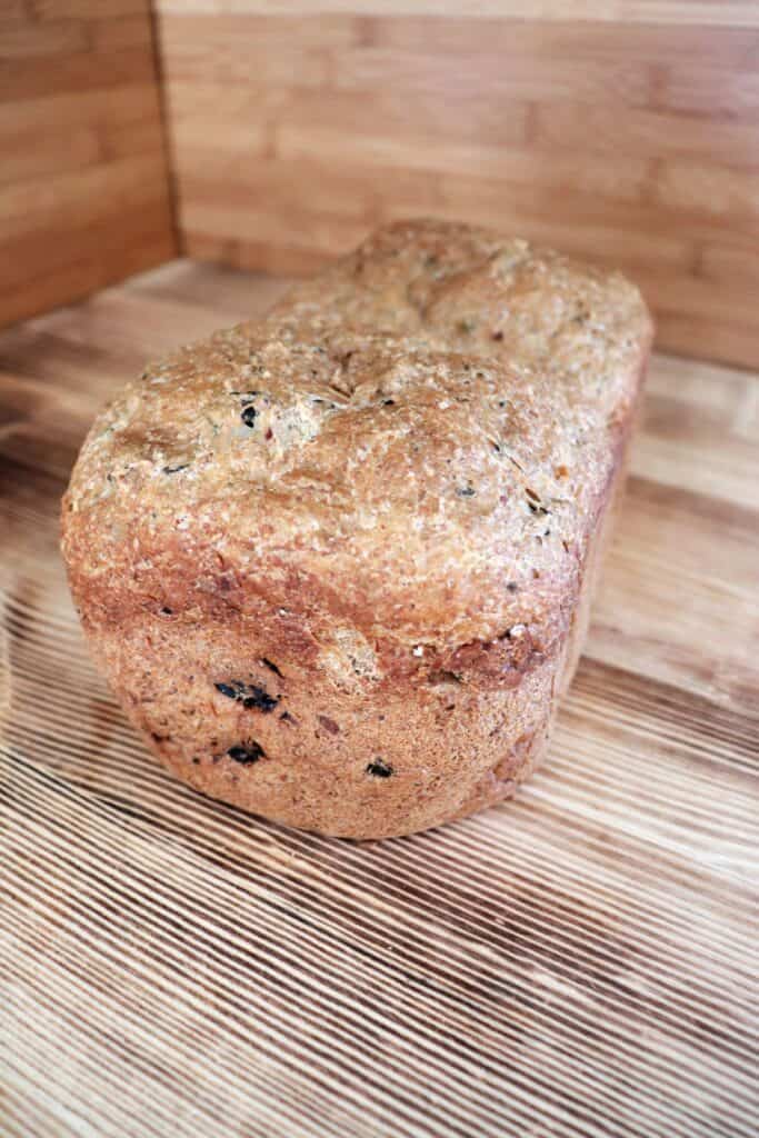 A loaf of zucchini raisin bread sits on a board. 